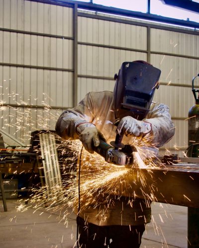 Welder using a grinder in a workshop, sparks flying, Lampa, Chile.