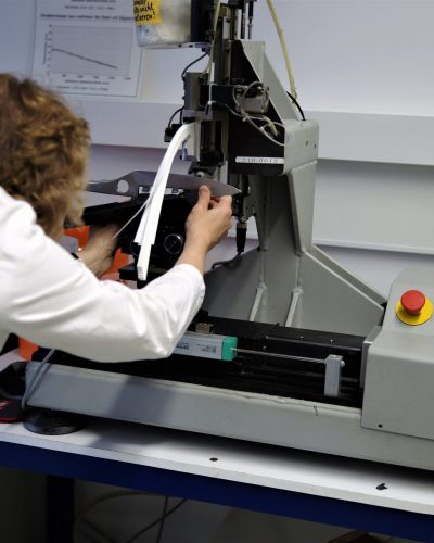 Scientist operates a precision testing machine in a modern laboratory setting.