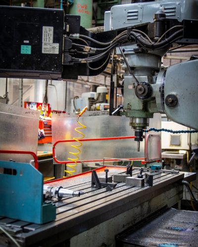 Close-up of an industrial CNC lathe in a bustling machine shop setting, focused on precision metalwork.