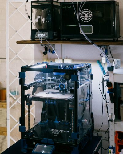 A modern 3D printer setup in a technology workshop with various tools and devices.